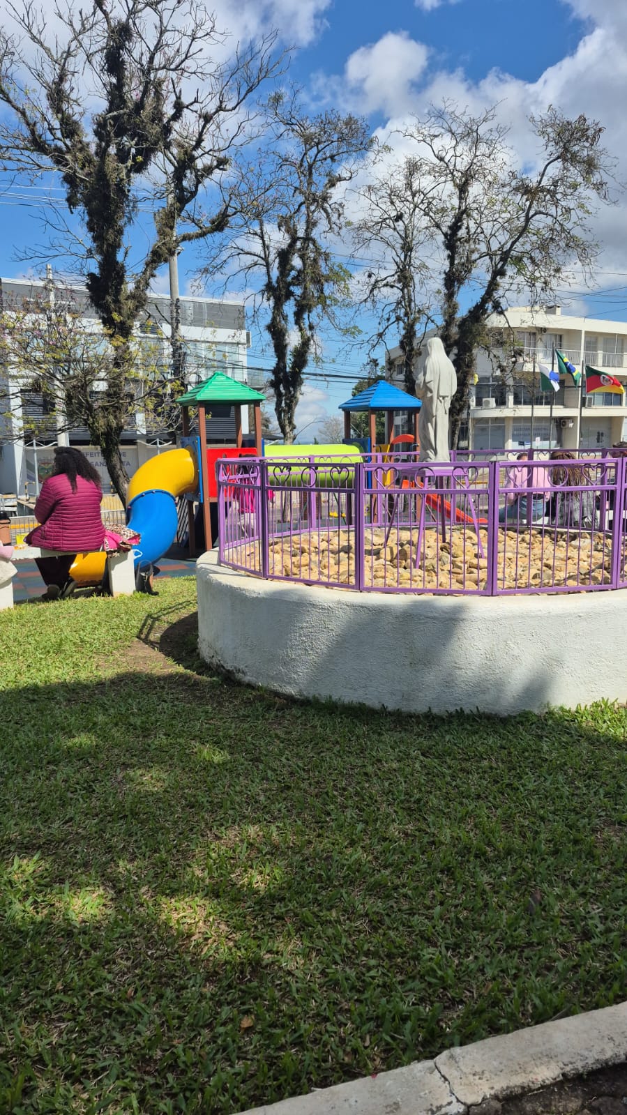 Playground e área de convivência revitalizados da Praça da Bíblia em Nova Santa Rita, com a imagem de Santa Rita de Cássia ao fundo